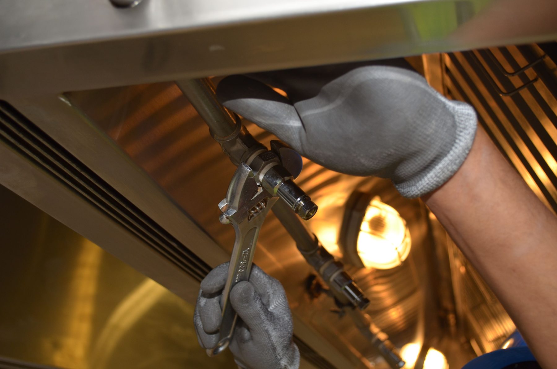 Close-up of tradesperson using a wrench on pipework